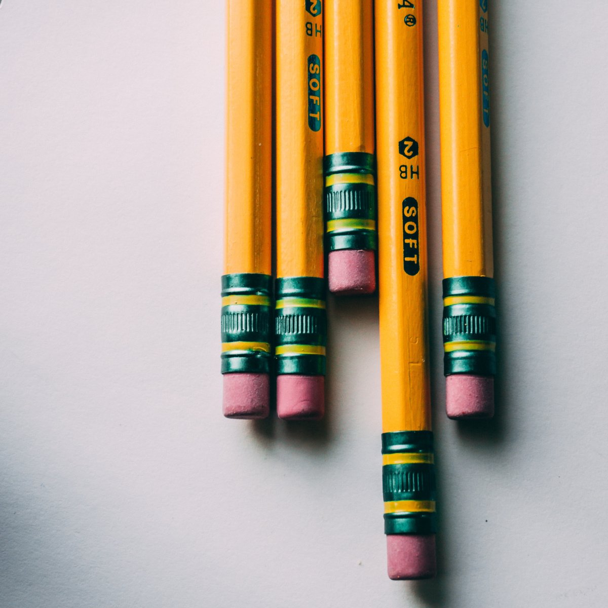 Five pencils stacked next to one another. Close up of eraser with white background.
