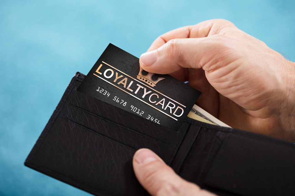 A man pulling a loyalty card out of his wallet is returning to his favorite merchant due to their retail loyalty strategies.